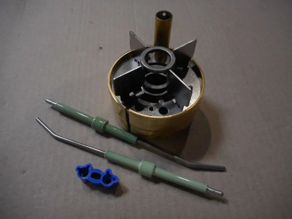 Remeha Brennerkopf mit Elektroden, bestehend aus einem zylindrischen Körper und verschiedenen Stabilisierungselementen. Zubehörteile getrennt angeordnet.